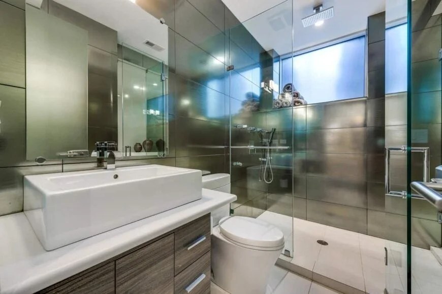 Dark tiled walls contrast with glass shower for stylish effect.