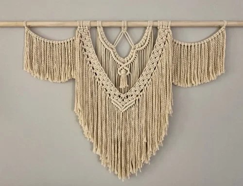 V-shaped knotted macrame wall hanging in soft tones.